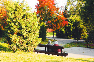 two grandmothers sitting on a bench in an autumn park