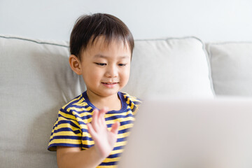 Wall Mural - Asian toddler boy student study online learning online education video call zoom teacher.Happy boy learn english online with laptop at home.New normal.Covid-19 coronavirus.Social distancing.stay home.