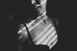 © Jess Craven/Stocksy - Line shadows from window blind on woman in black bra