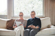 © Trinette Reed/Stocksy - Mature couple with grey hair looking at digital tablet and phone at home