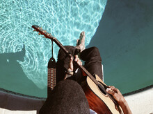 Guy Playing Guitar On Diving Board Over Pool