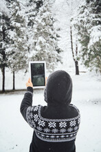 Woman Taking A Photo Of Snowy Trees