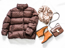 Women's Brown Down Jacket, Cashmere Scarf, Leather Shoulder Bag, Oxford Suede Boots On A Light Background, Top View. Autumn, Winter Women's Clothing Fashion Concept
