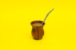 Yerba mate in clay calabash on yellow background