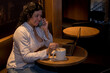 © Carlos - Caucasian woman in a coffee shop working with a laptop while talking on the phone and had a coffee