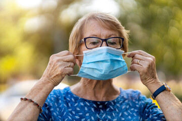 Wall Mural - Portrait of senior woman wearing protective face mask outdoors in city
