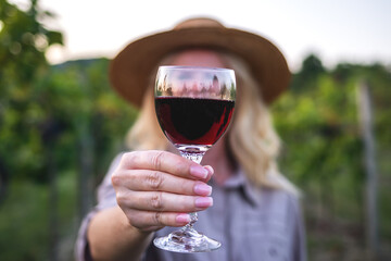 Cheers! Celebratory toast of red wine at vineyard. Woman holding wineglass outdoors