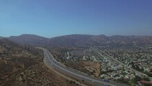 An Aerial View Of The Suburban Landscape And The Desert Mountains Divided By The Busy Highway That Fades In The Distance