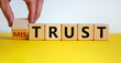 Hand turns a cube and changes the expression 'mistrust' to 'trust'. Beautiful yellow table, white background, copy space. Business concept.