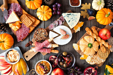 Wall Mural - Autumn theme charcuterie table scene against a dark wood background. Variety of cheese and meat appetizers. Overhead view.