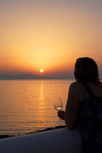 Woman With A Glass Of White Wine Gazing At A Sunset