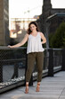 © aspenphoto - Stunning young woman poses for photo in late summer in elevated urban park - white blouse and green pants - smiling