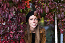 Portrait Of Pretty Smiling Young Woman With Head Framed By Red Vine Leaves During A Fall Afternoon, Quebec City, Quebec, Canada