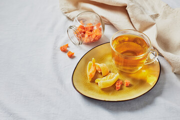 Wall Mural - Delicious black tea in glass cup and candied fruits on yellow saucer