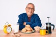 © Krakenimages.com - Senior handsome man with gray hair sitting on the table eating breakfast in the morning happy face smiling with crossed arms looking at the camera. positive person.