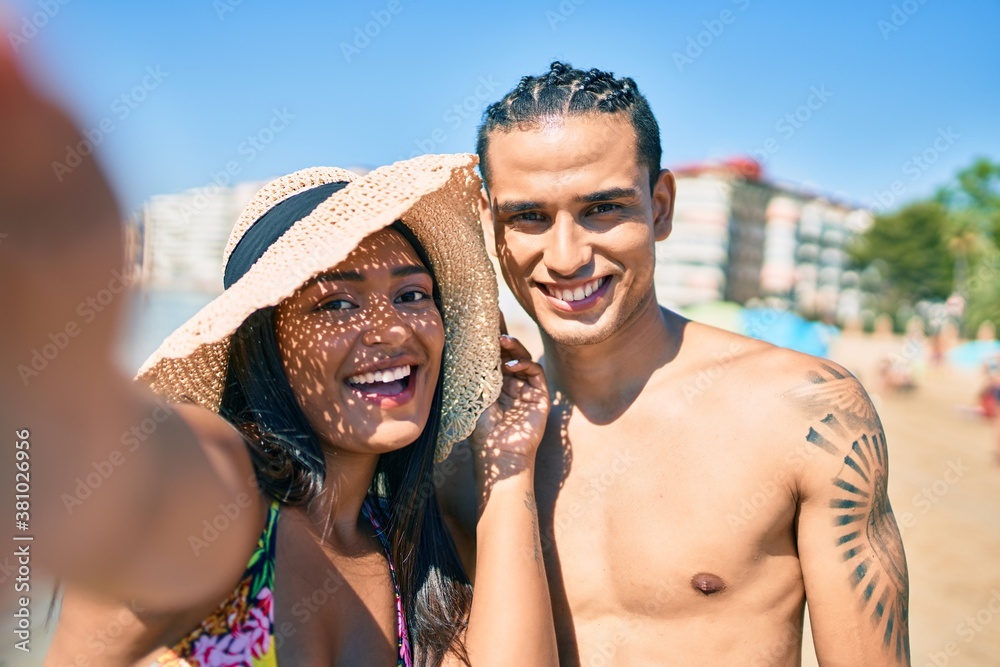 Young latin couple smiling happy making selfie by the camera at the beach.