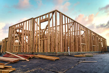 New Construction House Framing Of Residential Home In California With Beautiful Blue And Pink Sunset Sky Filled With Clouds And Lumber Laying Around The Construction Site Property