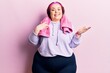 Young plus size woman wearing sportswear and towel celebrating achievement with happy smile and winner expression with raised hand