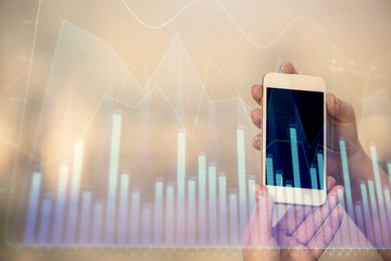 Double exposure of forex graph sketch hologram and woman holding and using a mobile device. Stock market concept.