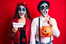 Couple Wearing Day Of The Dead Costume Holding Pumpking And Halloween Paper Celebrating Crazy And Amazed For Success With Open Eyes Screaming Excited.
