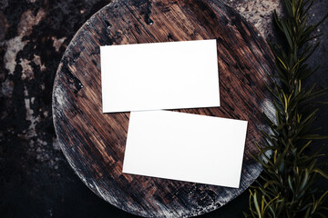 Photo of blank white business cards on a dark wooden cutting board circle. Blank template for  brand identity mock-up design,  food theme. Presentation and portfolio template 