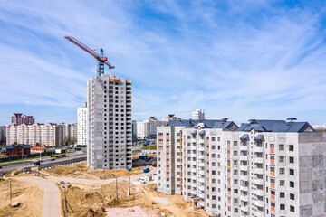 aerial view of tower crane and concrete apartment buildings under construction. urban development concept