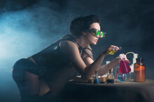 Young Brunette Alchemist With Bottles On A Black Background	