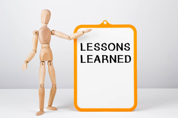 Aufkleber - Wooden man shows with a hand to white board with text LESSONS LEARNED