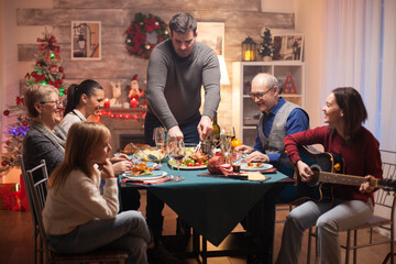 Big family at christmas celebration listening girl singing on guitar.