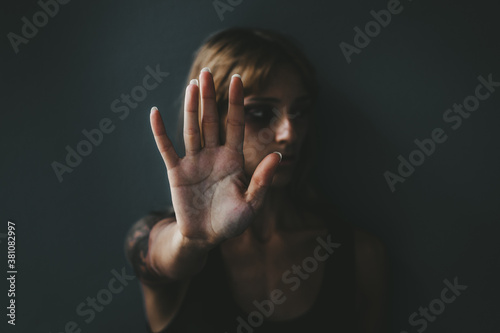 Fotomural Stop violence against women! Woman raised her hand for dissuade standing against dark wall