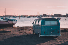 A Vintage Camper Van Parked Near The Sea At Sunset