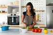 © NDABCREATIVITY - Beautiful young woman cooking at home. Healthy food, people concept