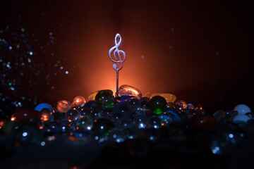 Wall Mural - Musical symbol treble clef stainless steel miniature with colorful toned light on foggy background. Selective focus