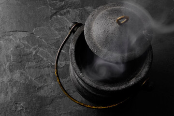 Smoking Black Iron Cauldron on a Dark Gray Slate Background