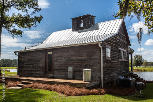 Rear scenic view of the exterior of a rural rustic wooden camp house used for fishing and hunting. The house is located on a large pond