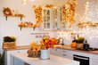 © sergiophoto - Autumn kitchen interior. Red and yellow leaves and flowers in the vase and pumpkin on light background