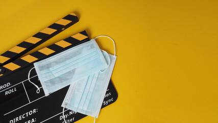 Black and yellow color Clapper board or movie slate with face mask. it use in video production and cinema industry on yellow background.