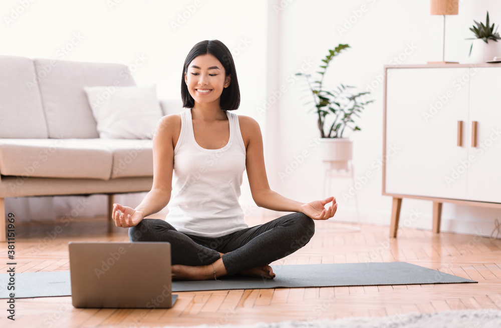 Millennial woman meditating with trainer online on laptop - obrazy, fototapety, plakaty 