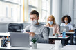 © Prostock-studio - Modern technology for work during quarantine covid-19. Young man manager in protective mask typing on smartphone at workplace with laptop
