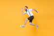 © ViDi Studio - Full length side view portrait of cheerful young bearded man 20s wearing white shirt suspender shorts posing jumping like running looking camera isolated on bright yellow color wall background studio.