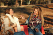 © djile - Two young women sitting on a bench in the park and talking after shopping