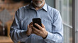 © fizkes - Crop close up of mature Caucasian grandfather hold modern smartphone gadget browse wireless internet. Senior man look at cellphone screen, read news online on device. Elderly and technology concept.