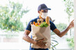 American courier guy wearing face mask carrying grocery bag of food to customer home and ringing doorbell.Food delivery service under quarantine.Takeout meal.During Coronavirus COVID-19 epidemic.