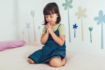 Cute little girl praying at home