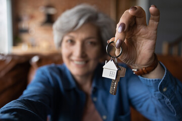 Close up blurred of happy elderly 60s grandmother show keys excited about house bank mortgage or lease, smiling mature woman tenant renter overjoyed to be home owner, relocation, rental concept