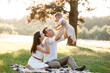 © Andriy Medvediuk - mom, dad lifts high his baby boy up mid air and looks at her smiling. Happy parents spending time playing with son in park on summer day. selective focus