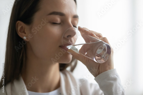 Fotomural Close up of thirsty millennial Caucasian girl hold glass drink clean mineral water for body refreshment and healthy skin