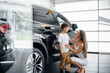 © Andrii - A happy mother with her young son chooses a new car at a car dealership. Buying a car