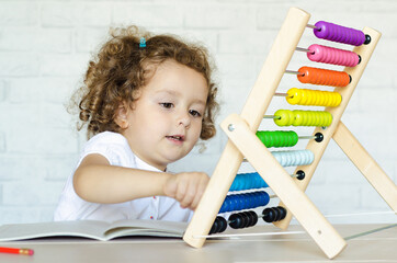 preschooler child learns to count. beautiful girl plays with mathematical abacus. kid and math. development, education, teaching and training of children.