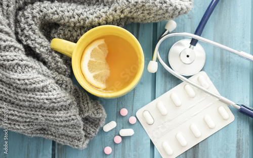 Fotografía Cold tea, pills, knitted scarf and stethoscope. Cold season.